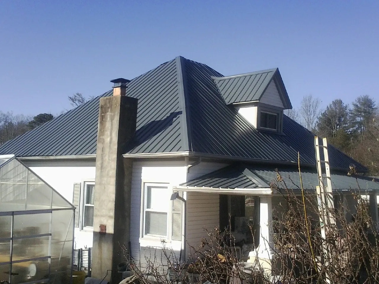 Dark blue standing seam metal roof on a white farmhouse with dormer — Slate & Tile Roof Repair by Roofing Brothers in Irvine