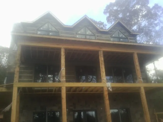 Dormers and porch framing on a large log home under construction — Roof Coating work by our crew in Irvine