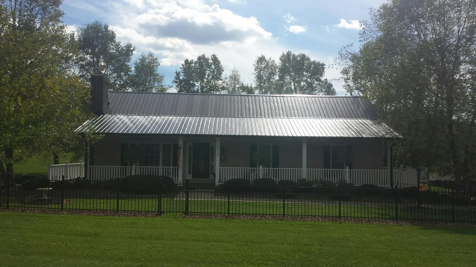 Gray metal roof on a brick ranch with a full width front porch — Gutter Guard Installation work by our crew in Irvine