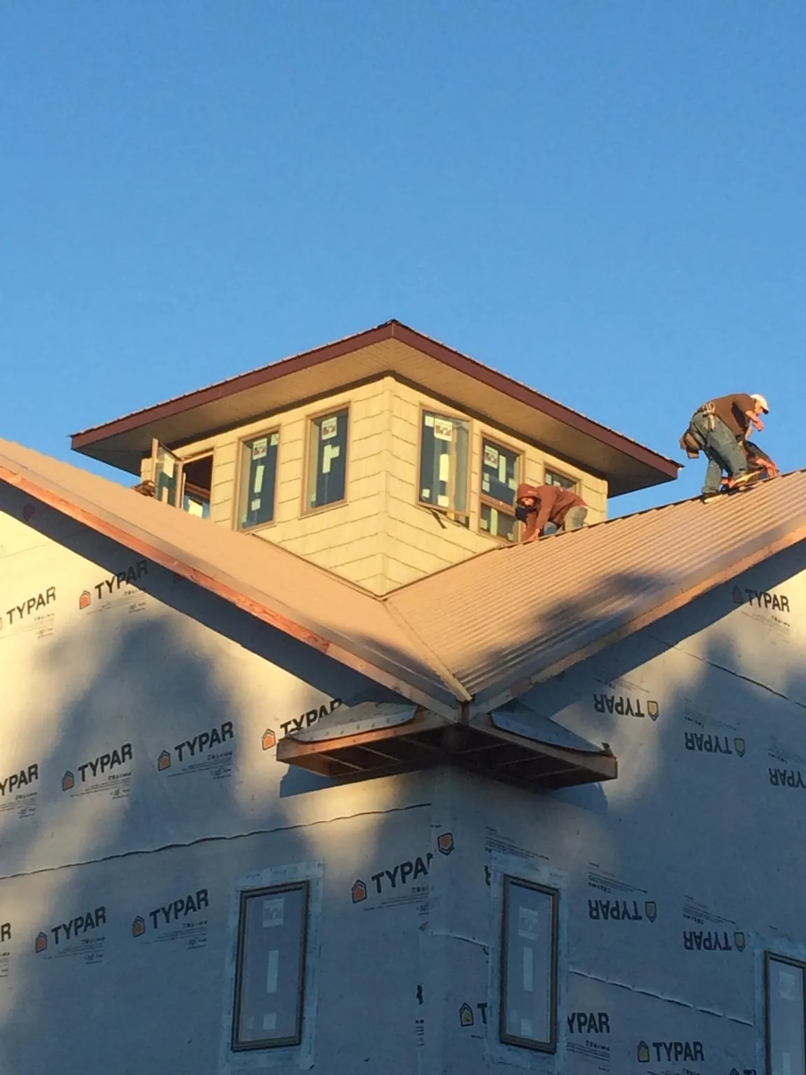 Roofers working around a rooftop cupola on a new metal roof at sunset — Roof Waterproofing in Irvine by Roofing Brothers